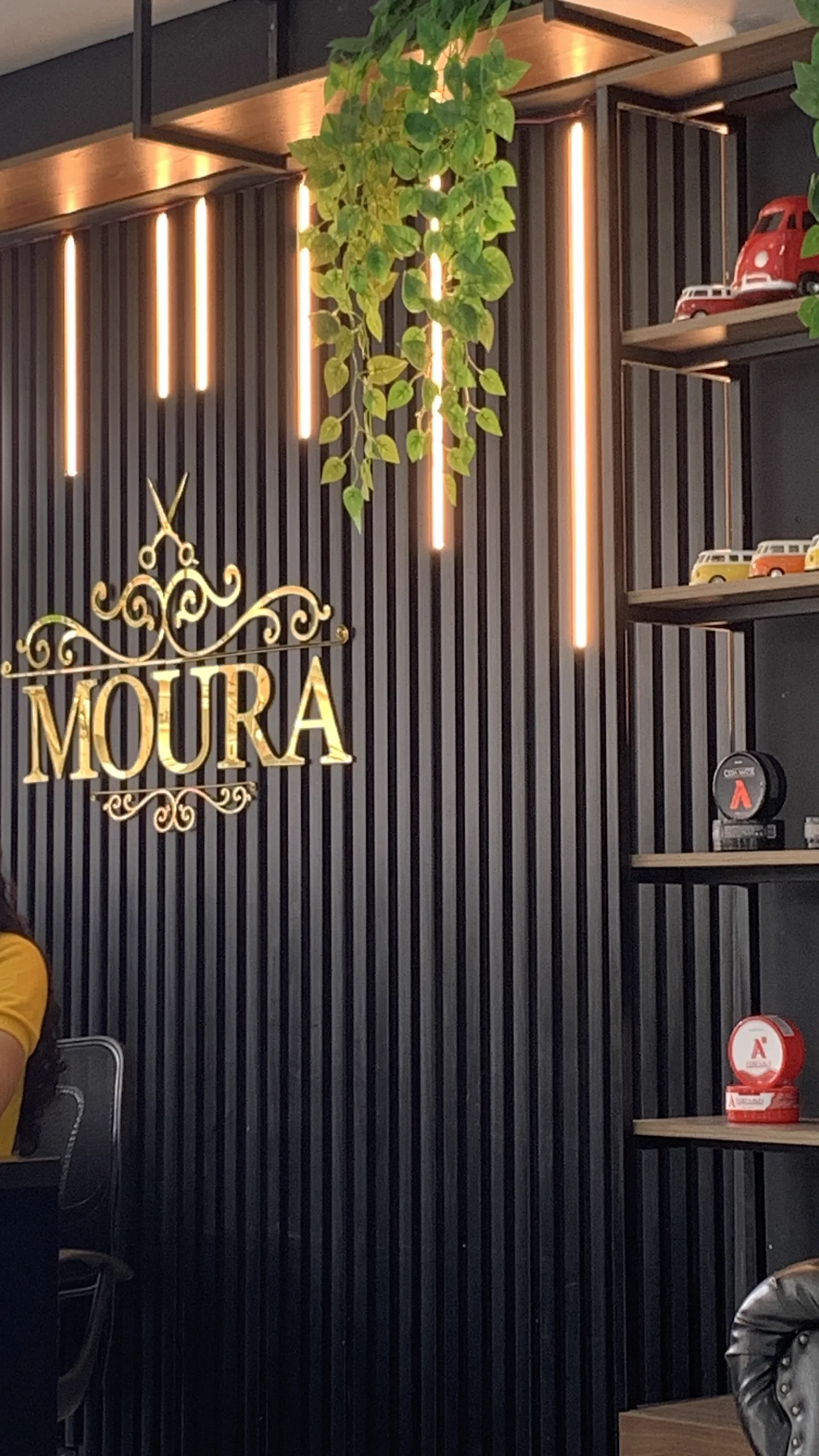 Letreiro dourado da Moura Barbearia na parede do salão