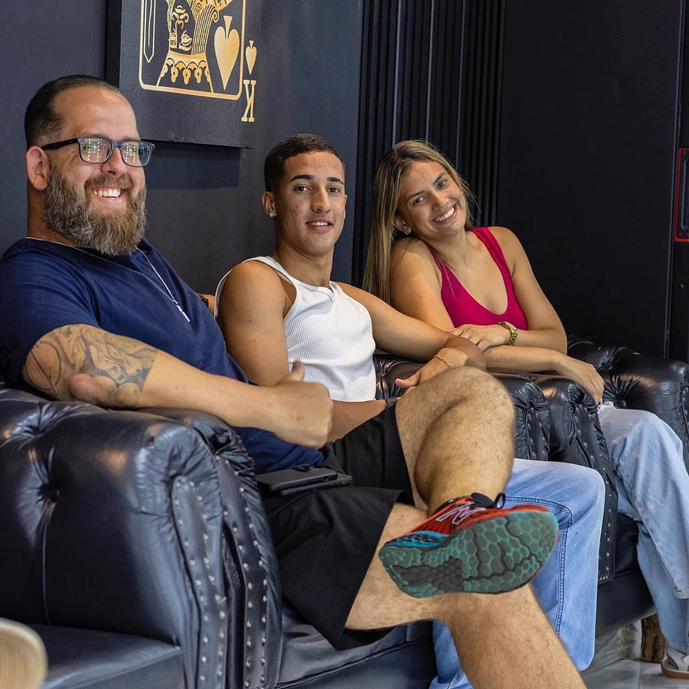 Pai, filho e mãe esperando no sofá da barbearia